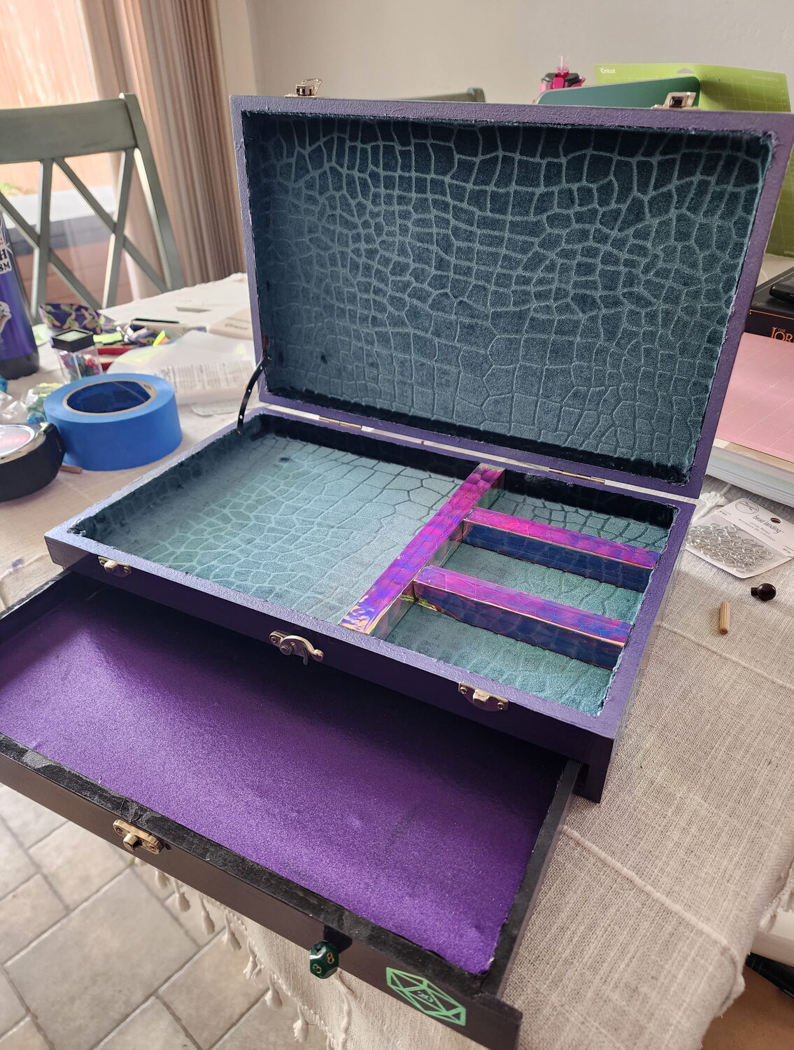 Open dice box showing a teal crackle-finish interior with dividers and a velvet-lined drawer