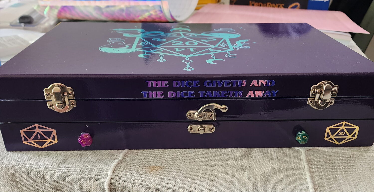Two matched violet dice boxes stacked, brass latches and gilded d20 corners